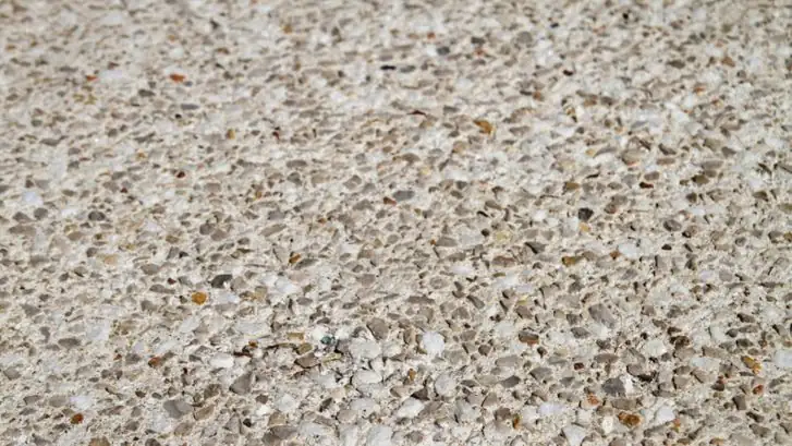 Detalle de un pavimento de hormigón desactivado con árido visto en tonos blancos, grises y ocres