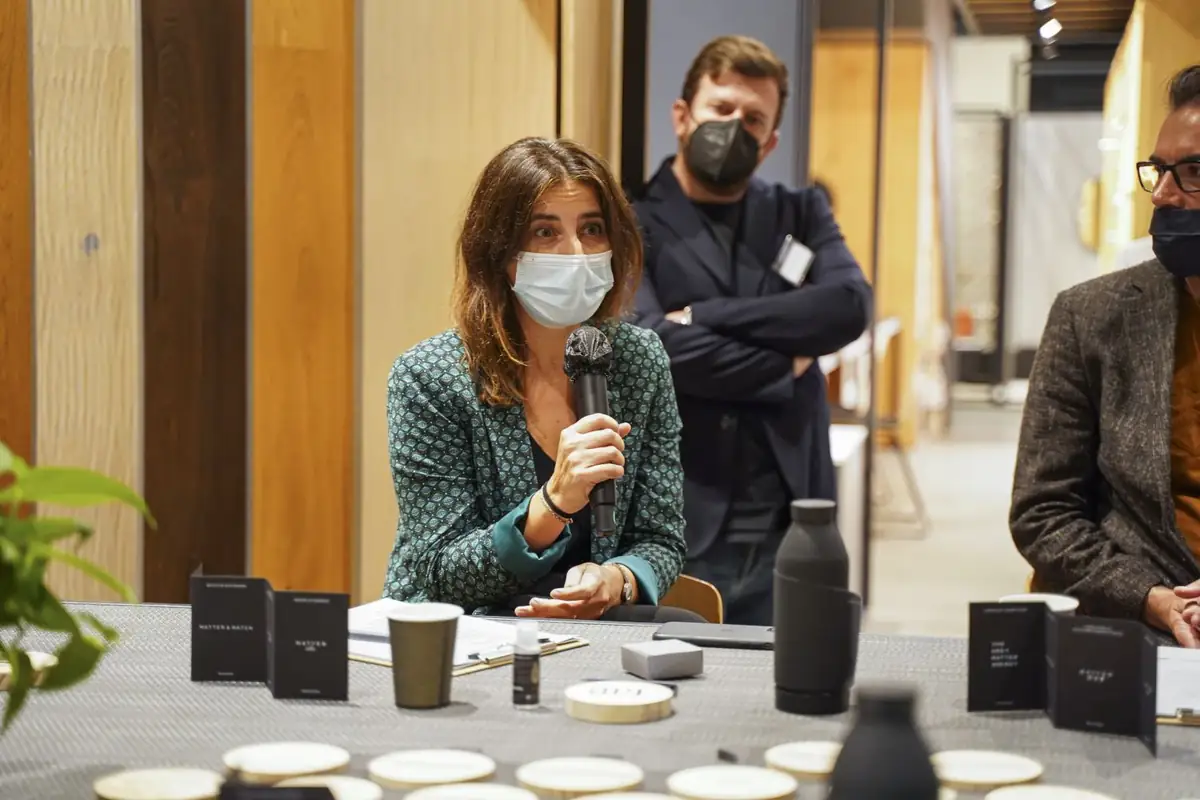 Una participante con mascarilla interviene con micrófono desde la mesa