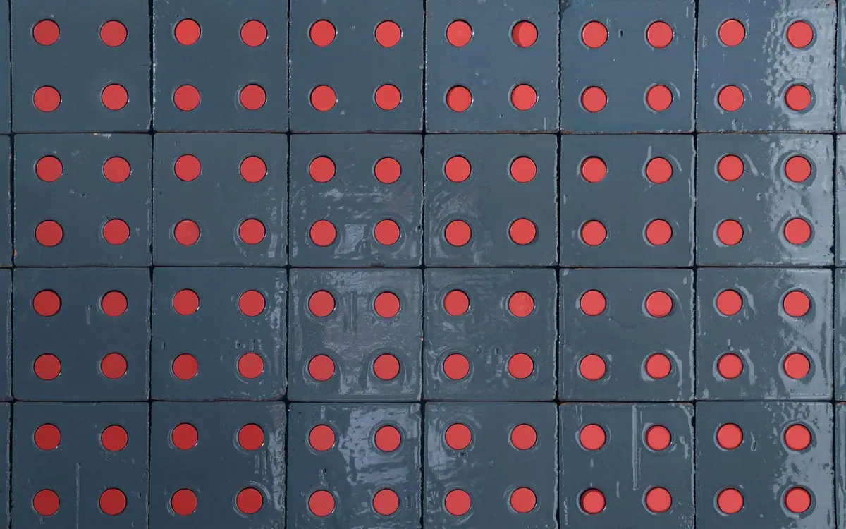 Muro de ladrillos azules esmaltados con los agujeros rellenos de tapones rojos