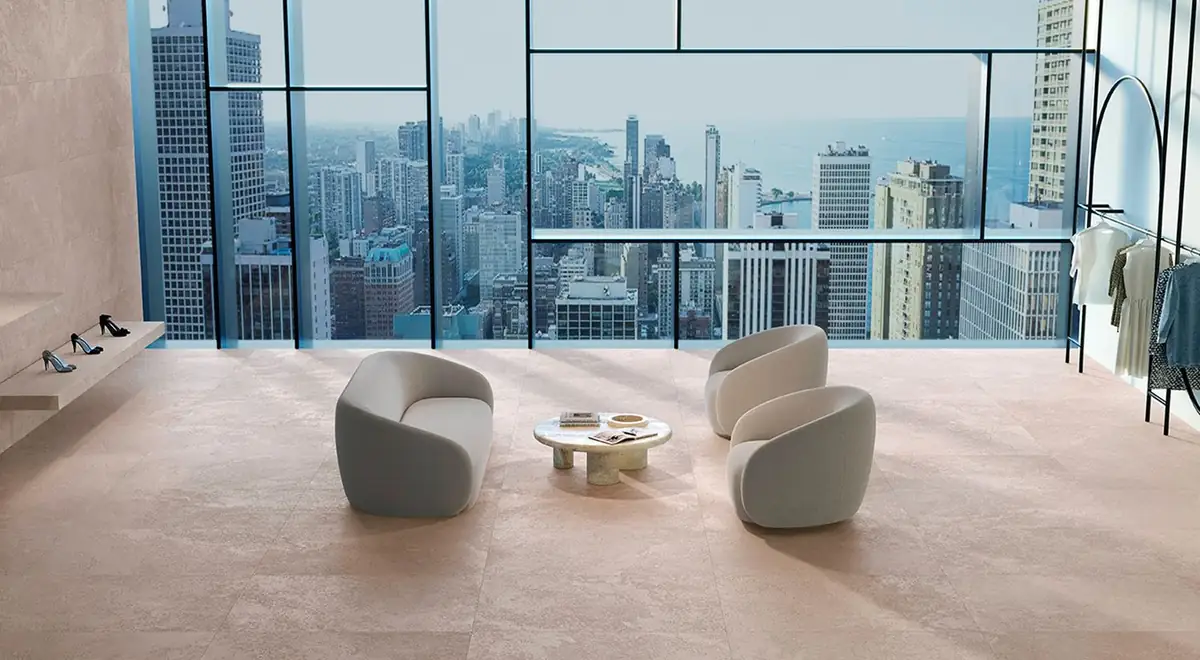 Sala con suelo y pared de porcelánico efecto piedra en tono arena, butacas grises y ventanal con vistas a los rascacielos de Chicago