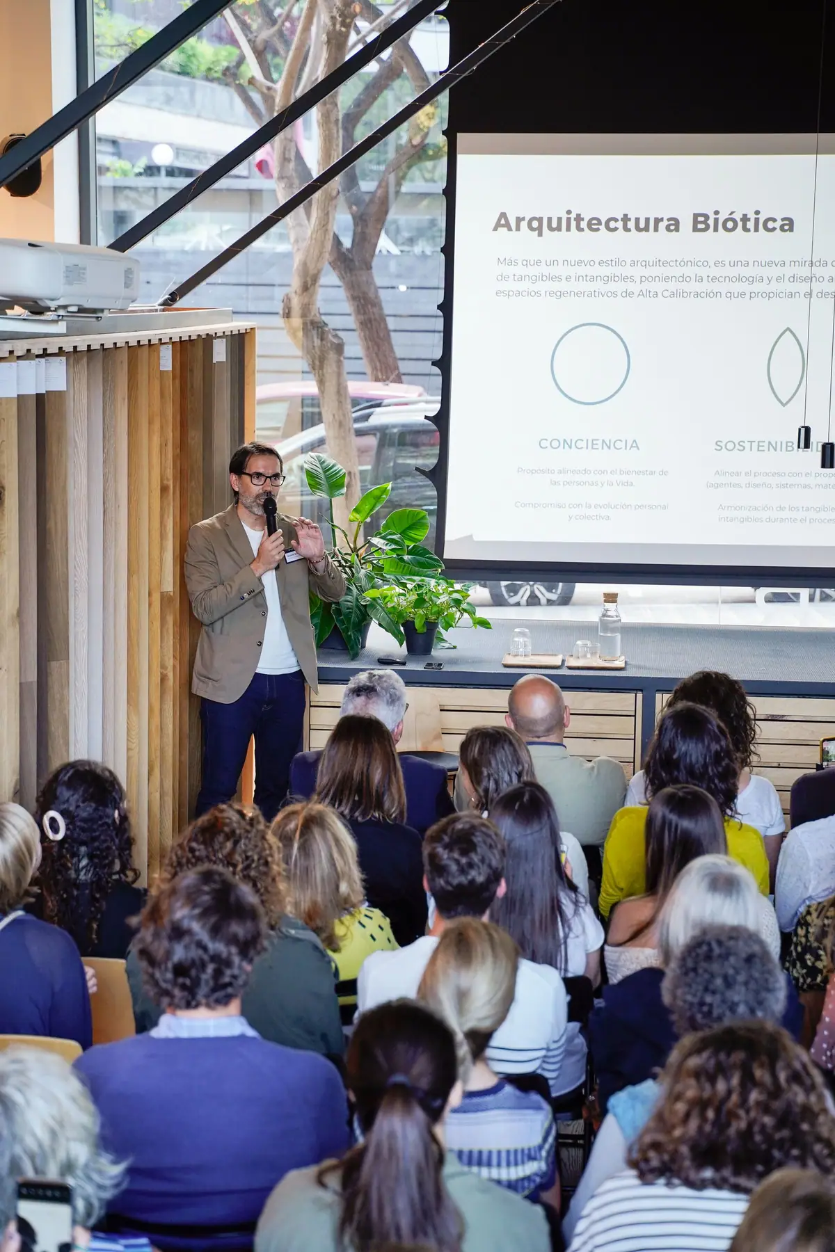 Ponente junto a una diapositiva titulada Arquitectura Biótica, ante el público