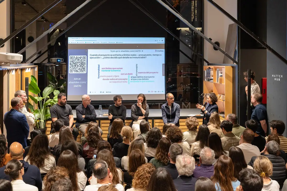 Ponentes sentados en la mesa redonda ante el público, con una nube de respuestas de los asistentes proyectada en pantalla