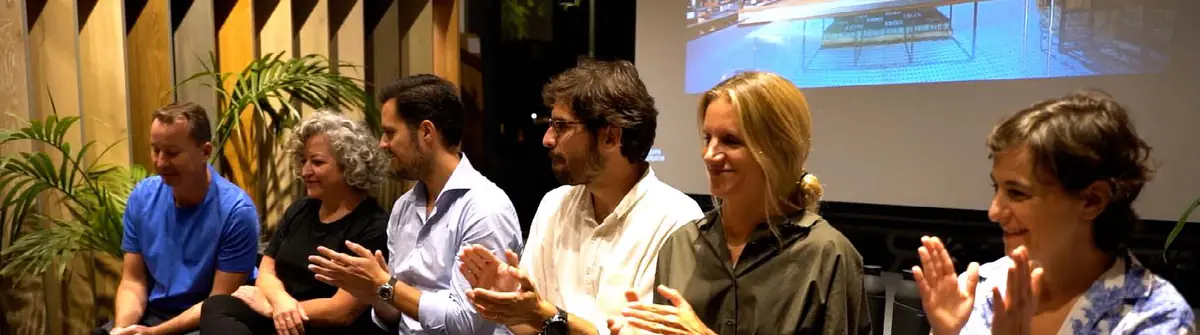 Los seis ponentes sentados en fila aplauden ante una pantalla de proyección en Matter Barcelona