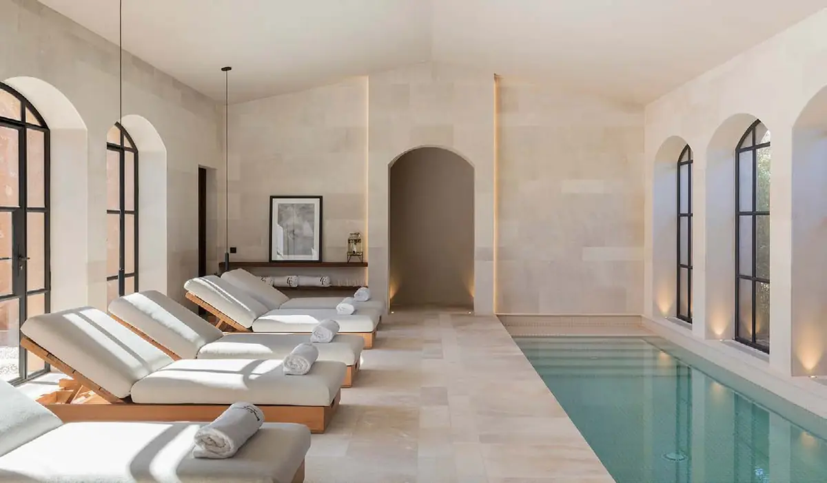 Piscina interior con tumbonas blancas bajo bóvedas de piedra clara