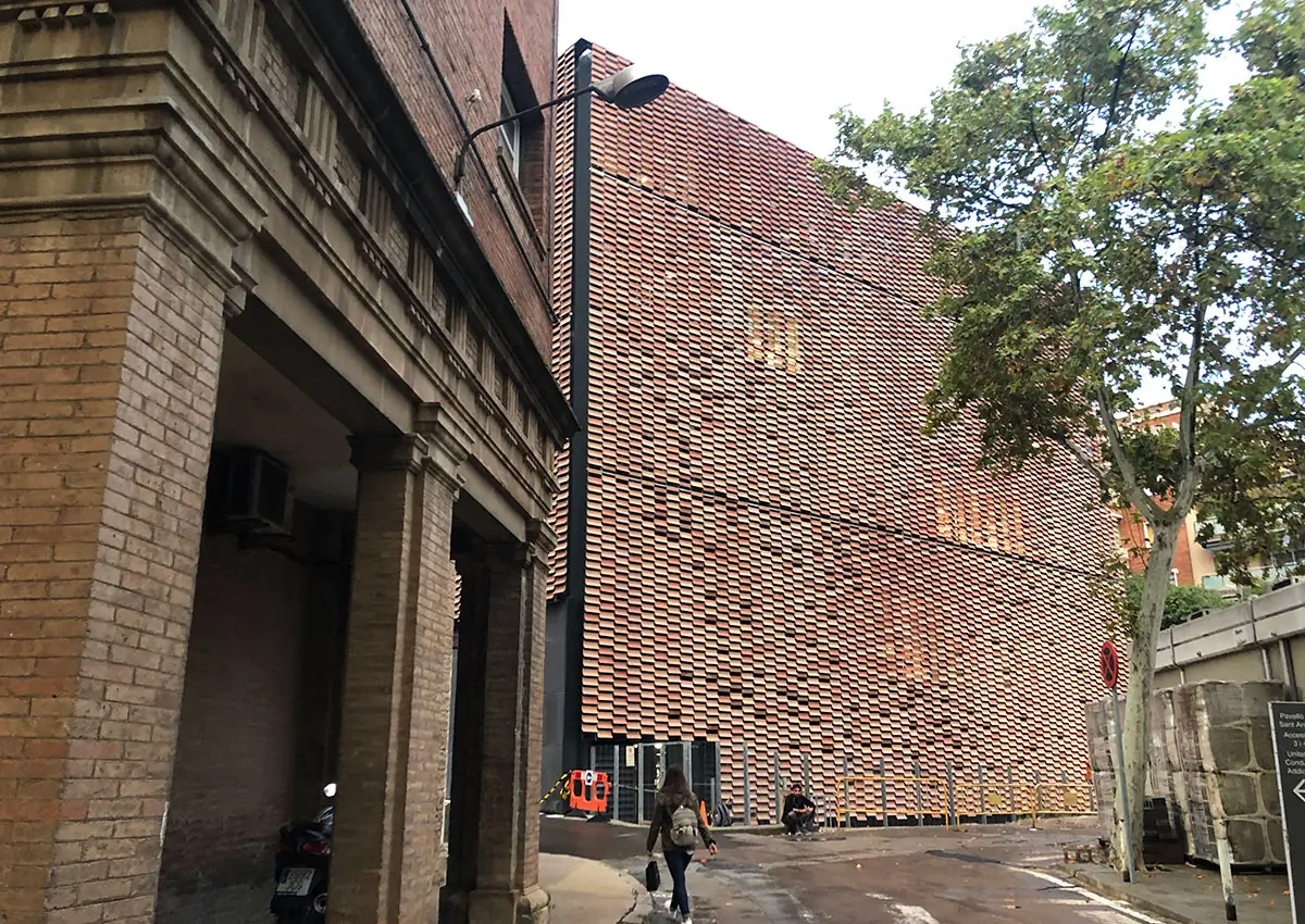 Fachada de celosía cerámica del Instituto de Investigación de Sant Pau junto a un edificio histórico de ladrillo