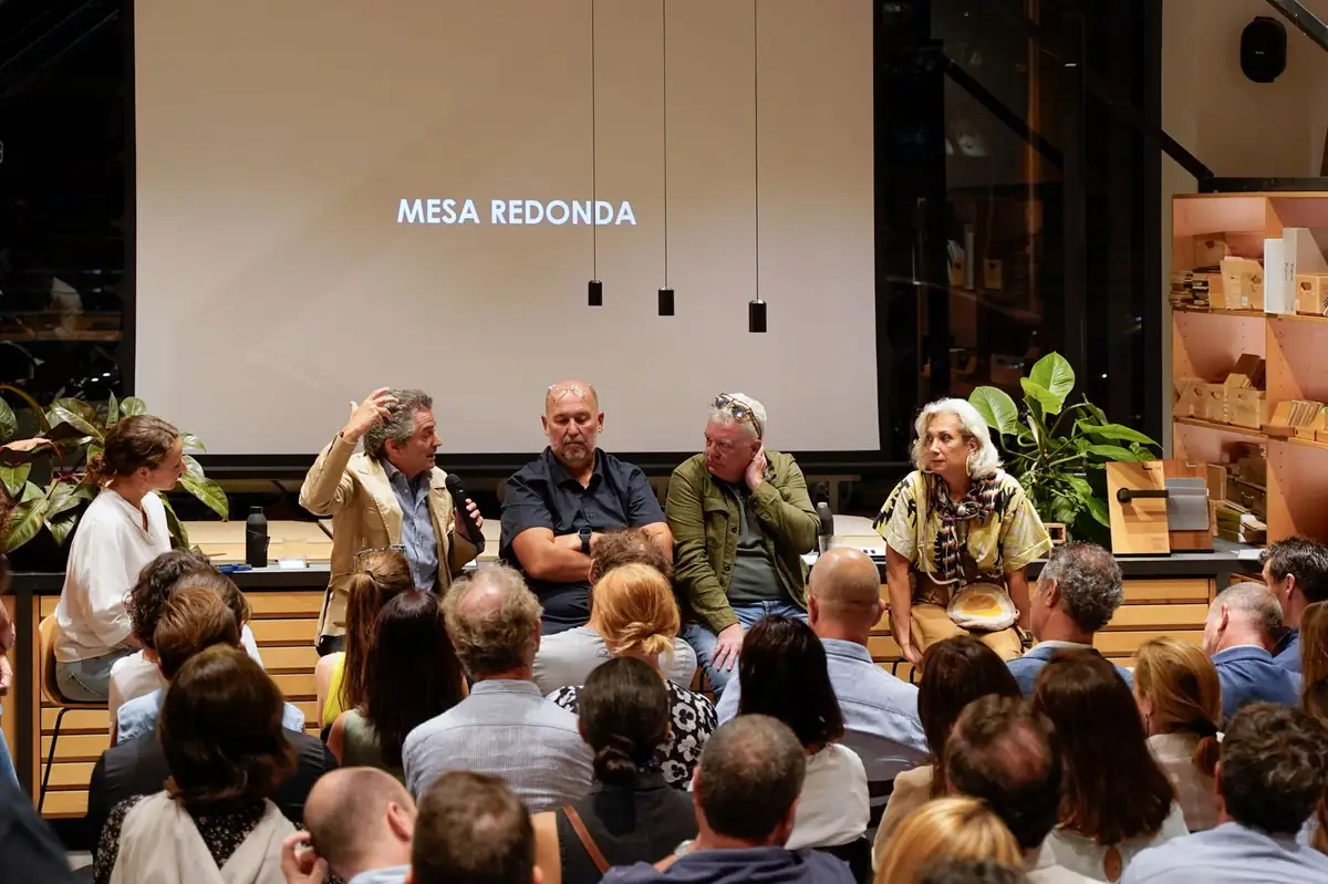 Los ponentes y la moderadora sentados ante una pantalla con el rótulo Mesa redonda