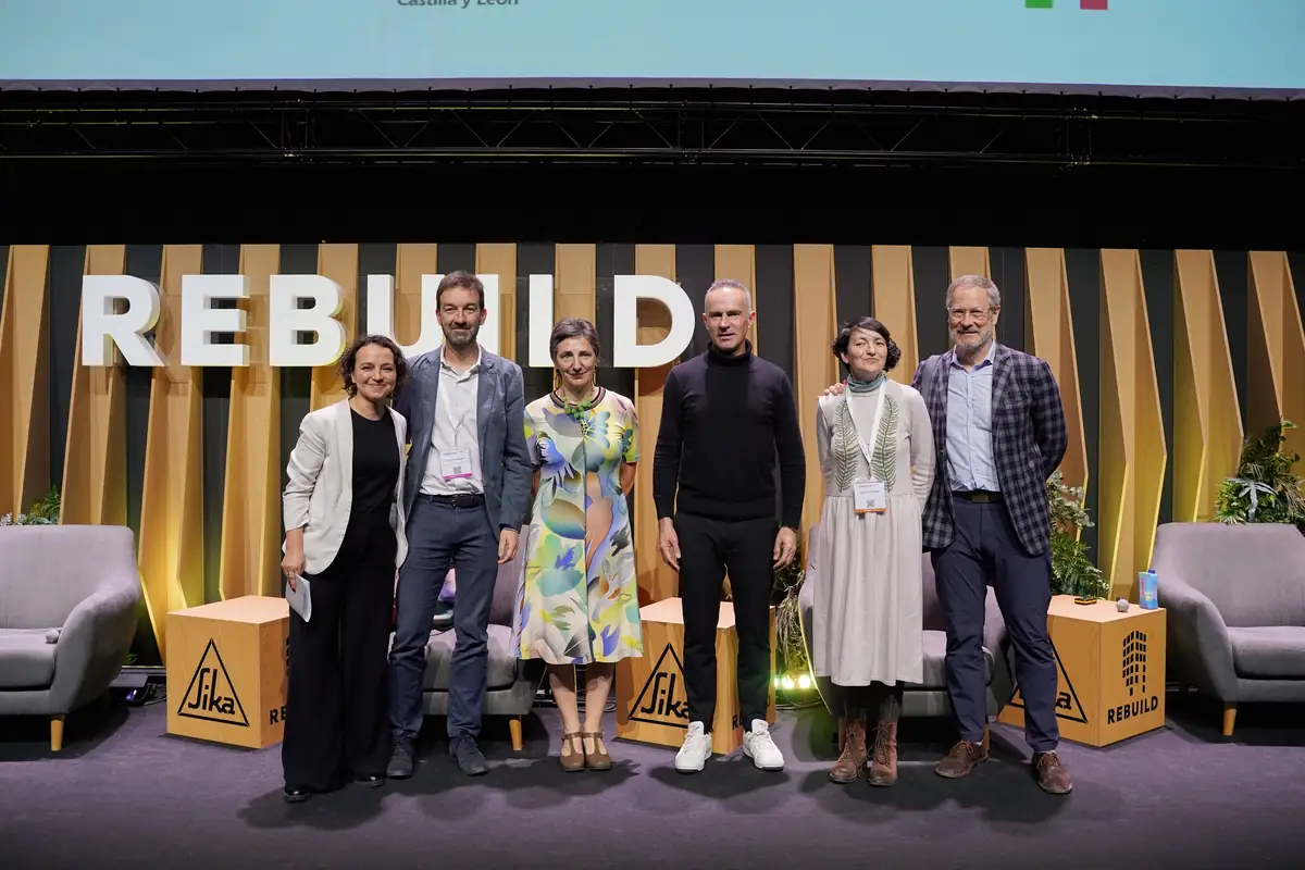 Los ponentes de la mesa posan de pie en el escenario de Rebuild