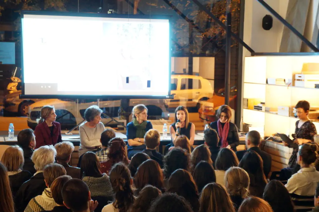 Las ponentes sentadas ante la pantalla mientras una de ellas habla al público en la Sala Matter