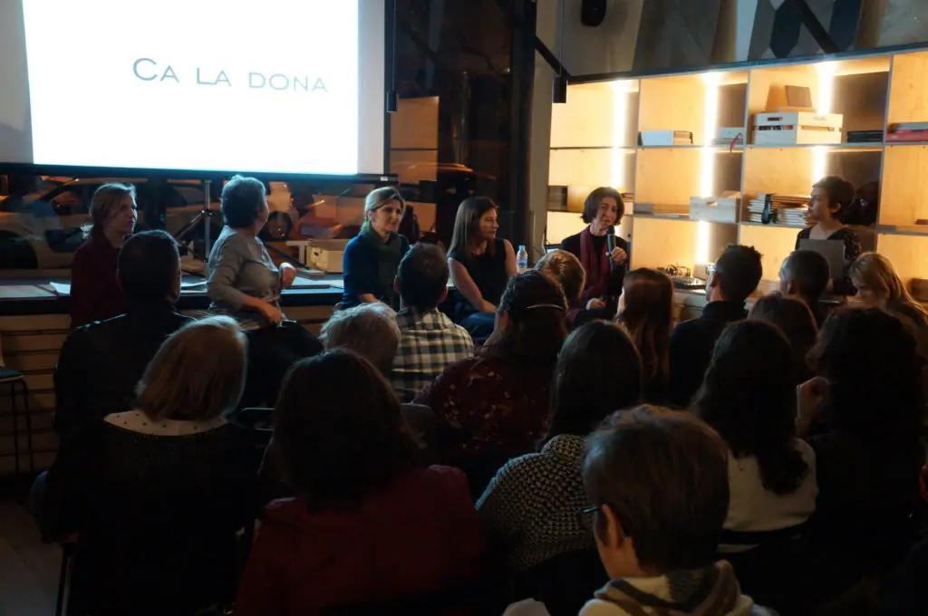Las ponentes sentadas bajo una pantalla con el título Ca la Dona durante la presentación