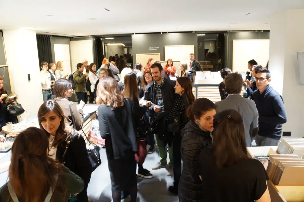 Grupo de asistentes conversando entre las mesas de materiales del showroom