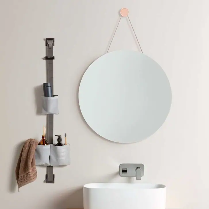 Banda TAPE STORAGE junto a un lavabo, con bolsas grises que guardan productos de aseo y una toalla colgada