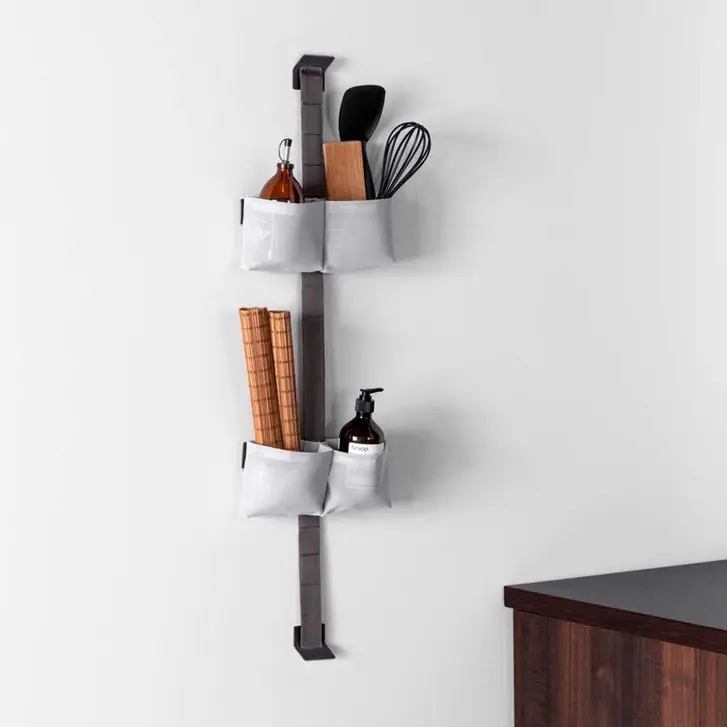 Banda TAPE STORAGE en la pared de una cocina con dos bolsas dobles grises con utensilios, aceite y salvamanteles