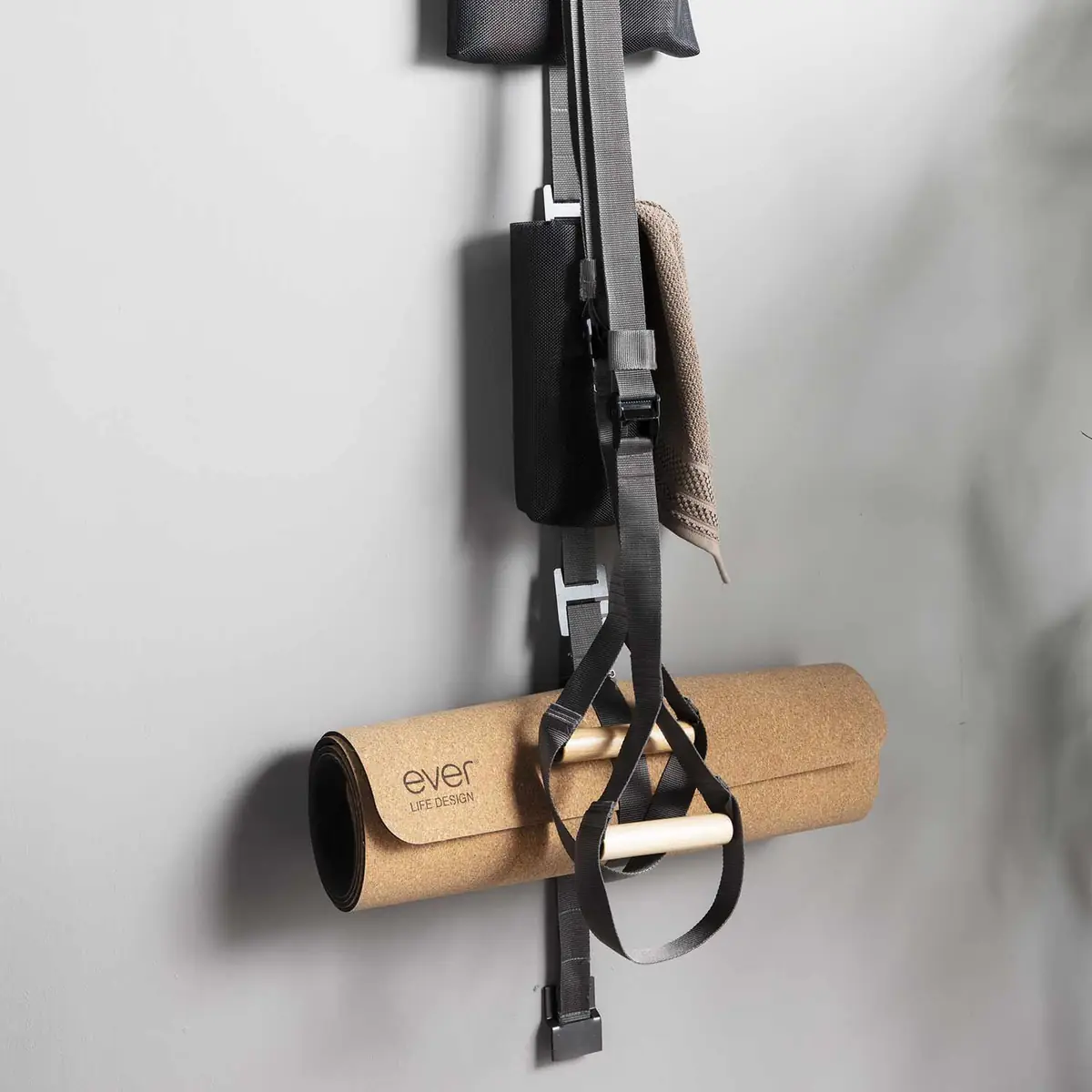 Esterilla de corcho enrollada y banda de entrenamiento con empuñaduras de madera colgadas de una banda TAPE en la pared