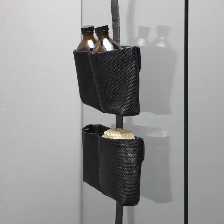 Banda TAPE SHOWER en el vidrio de una ducha con dos bolsas dobles negras que contienen botellas y una esponja