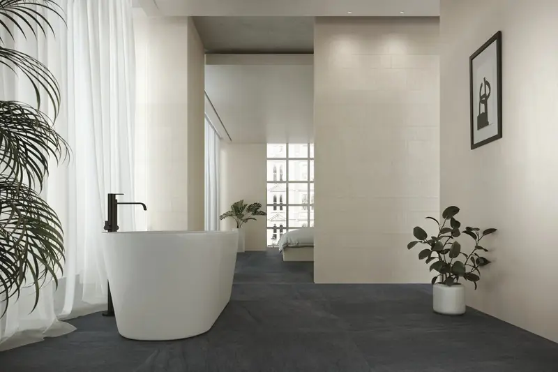 Baño con bañera exenta blanca y pavimento oscuro de porcelánico efecto piedra basáltica