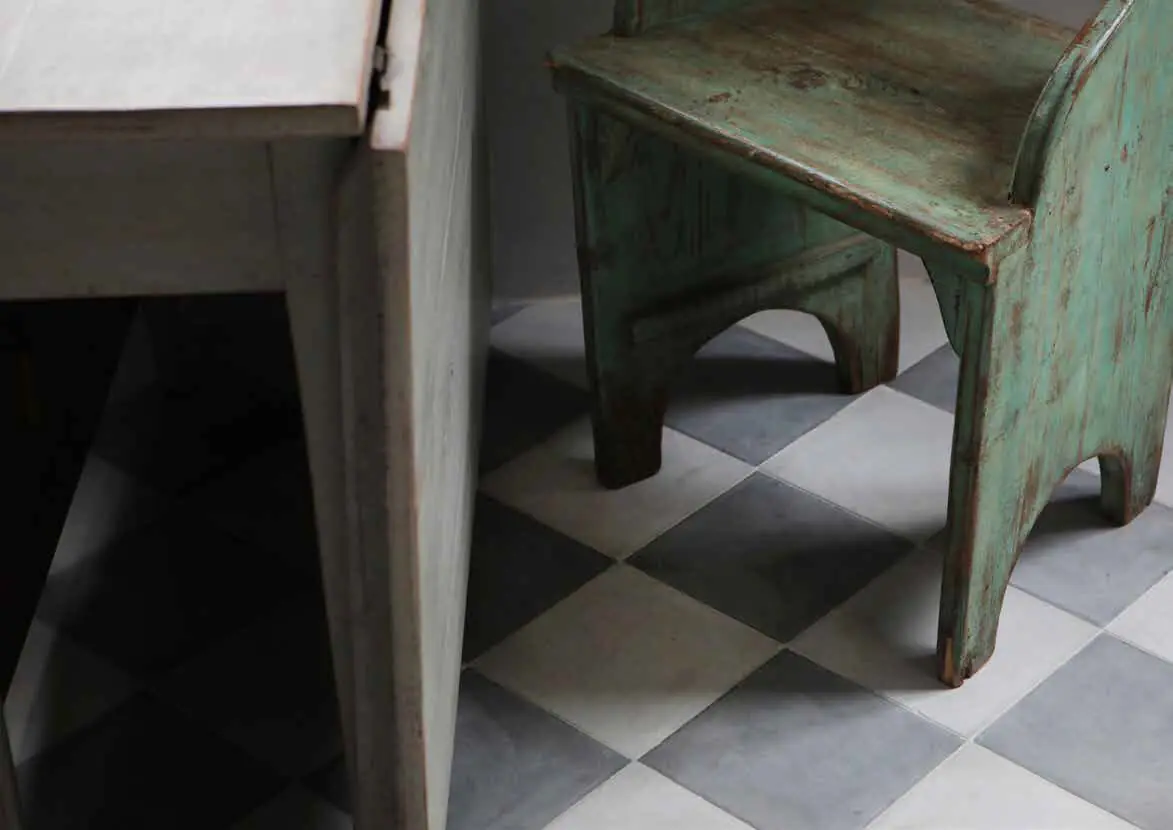 Suelo en damero de baldosas blancas y grises bajo una silla de madera verde