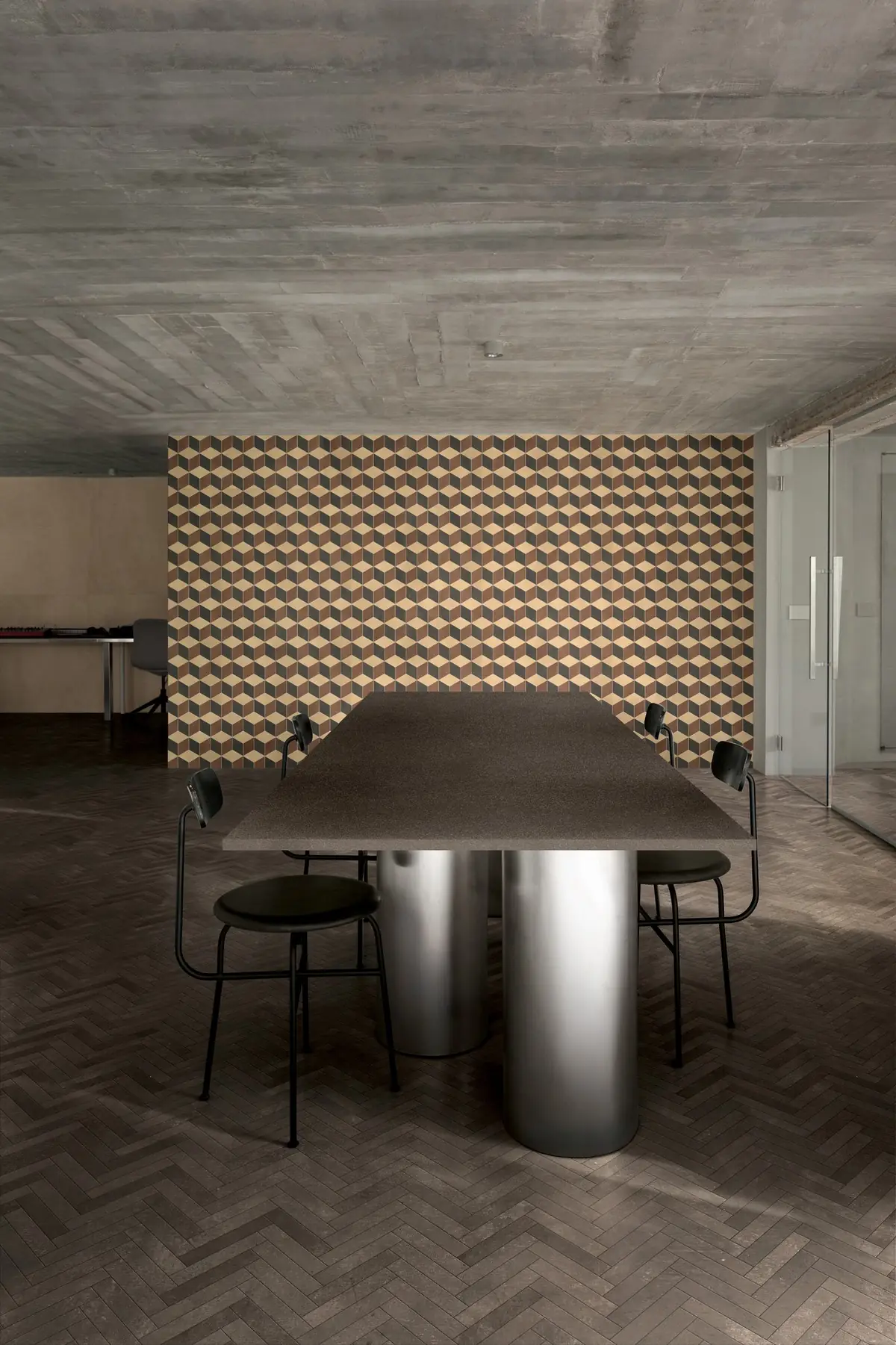 Sala de reuniones con pared de mosaico de rombos en tonos tierra y suelo oscuro en espiga
