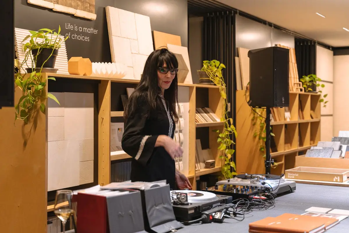 DJ Merli Marlowe en la mesa de mezclas, entre estanterías de muestras