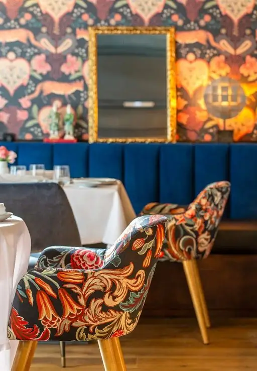 Butacas tapizadas con un estampado floral frente a una banqueta de terciopelo azul.