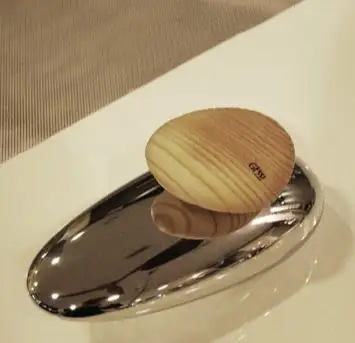 Mando ovalado de madera con el logotipo de Gessi sobre una base metálica cromada en el borde de una bañera