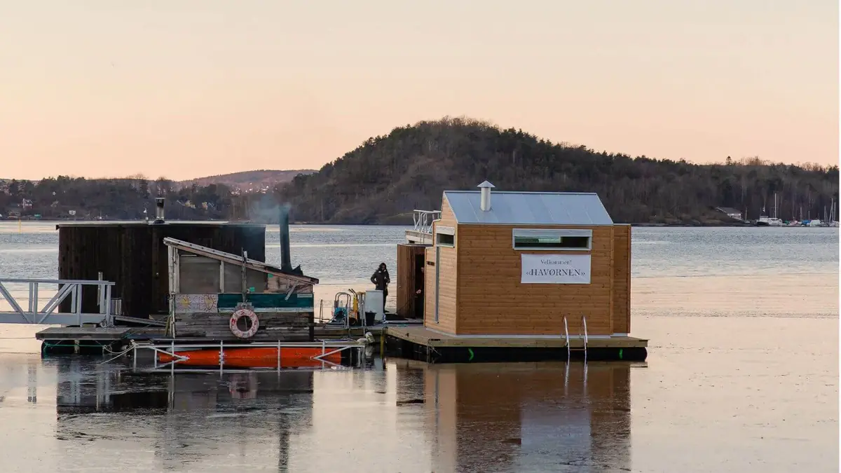 Sauna flotante de madera termotratada amarrada en el puerto de Oslo al atardecer