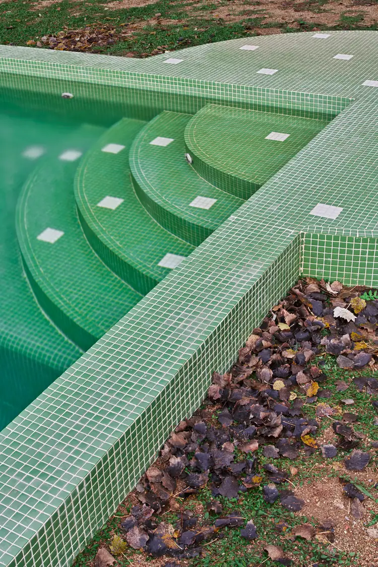 Escalones curvos de la piscina revestidos de gresite verde con piezas blancas