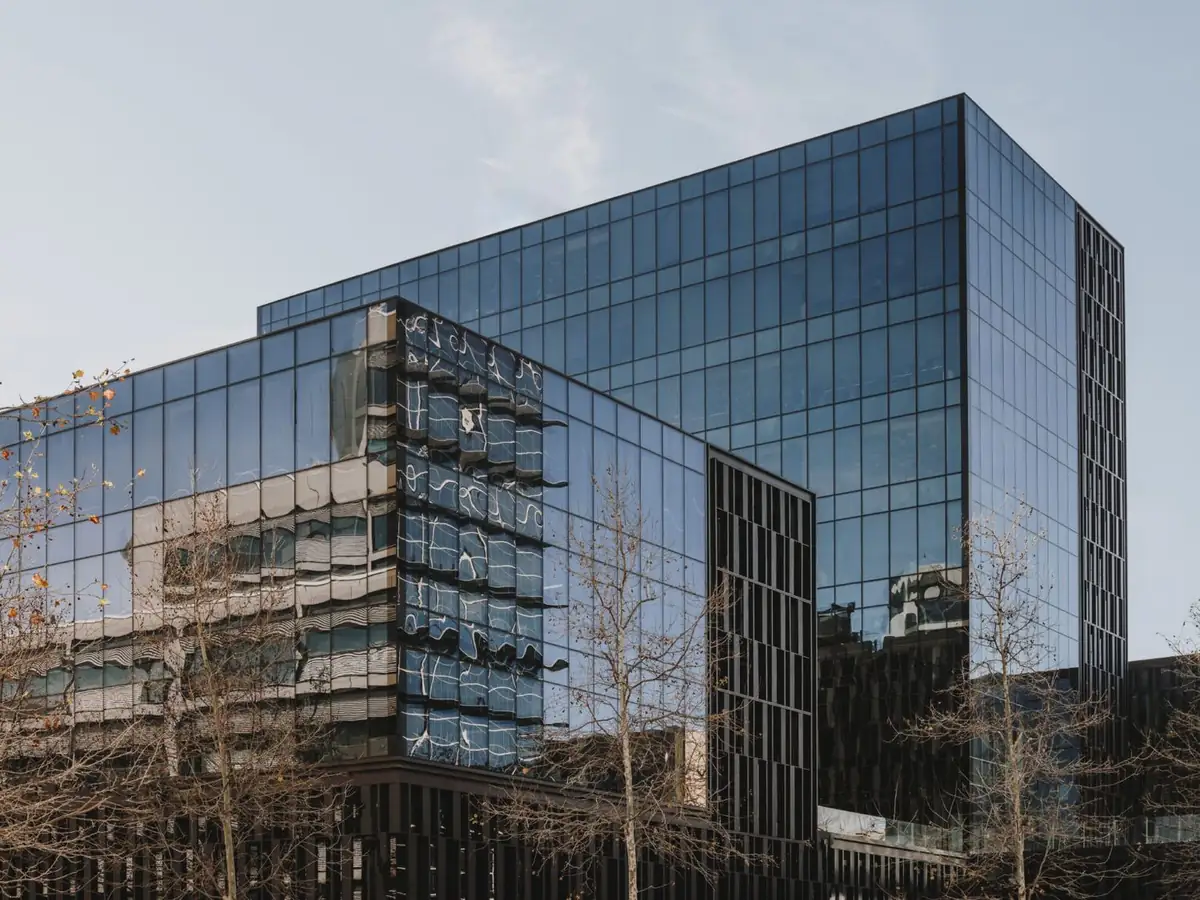 Torres de vidrio del Platinum@BCN con reflejos de los edificios vecinos y árboles sin hojas en primer plano