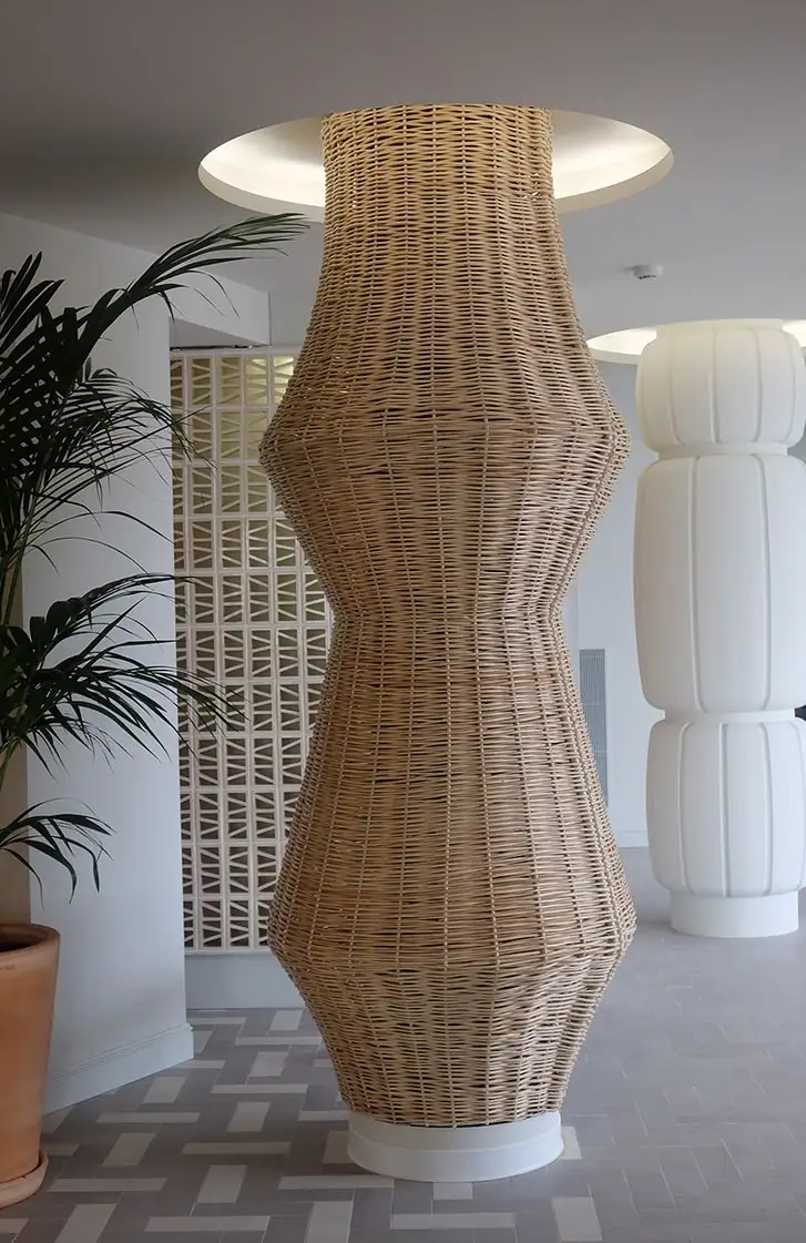 Columna revestida de mimbre trenzado junto a una celosía cerámica y una columna blanca de yeso