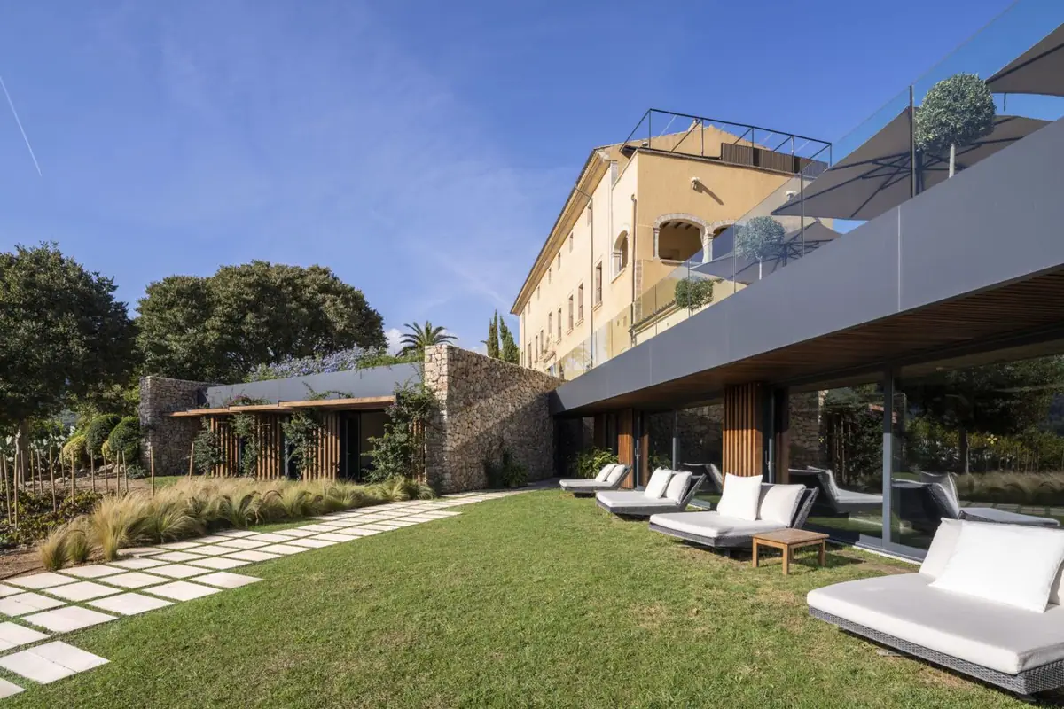 Ampliación del spa con pérgola de madera y jardín bajo la fachada del monasterio