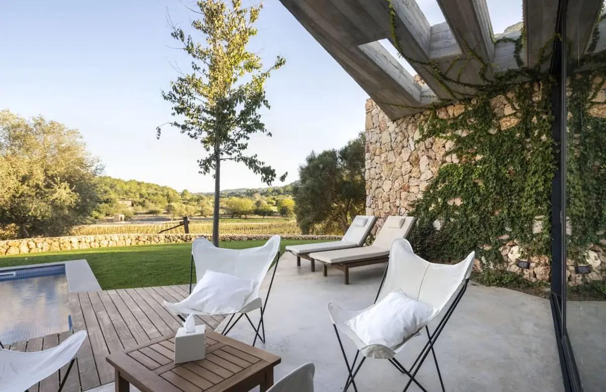 Terraza con sillas de mariposa junto a un muro de piedra cubierto de vegetación