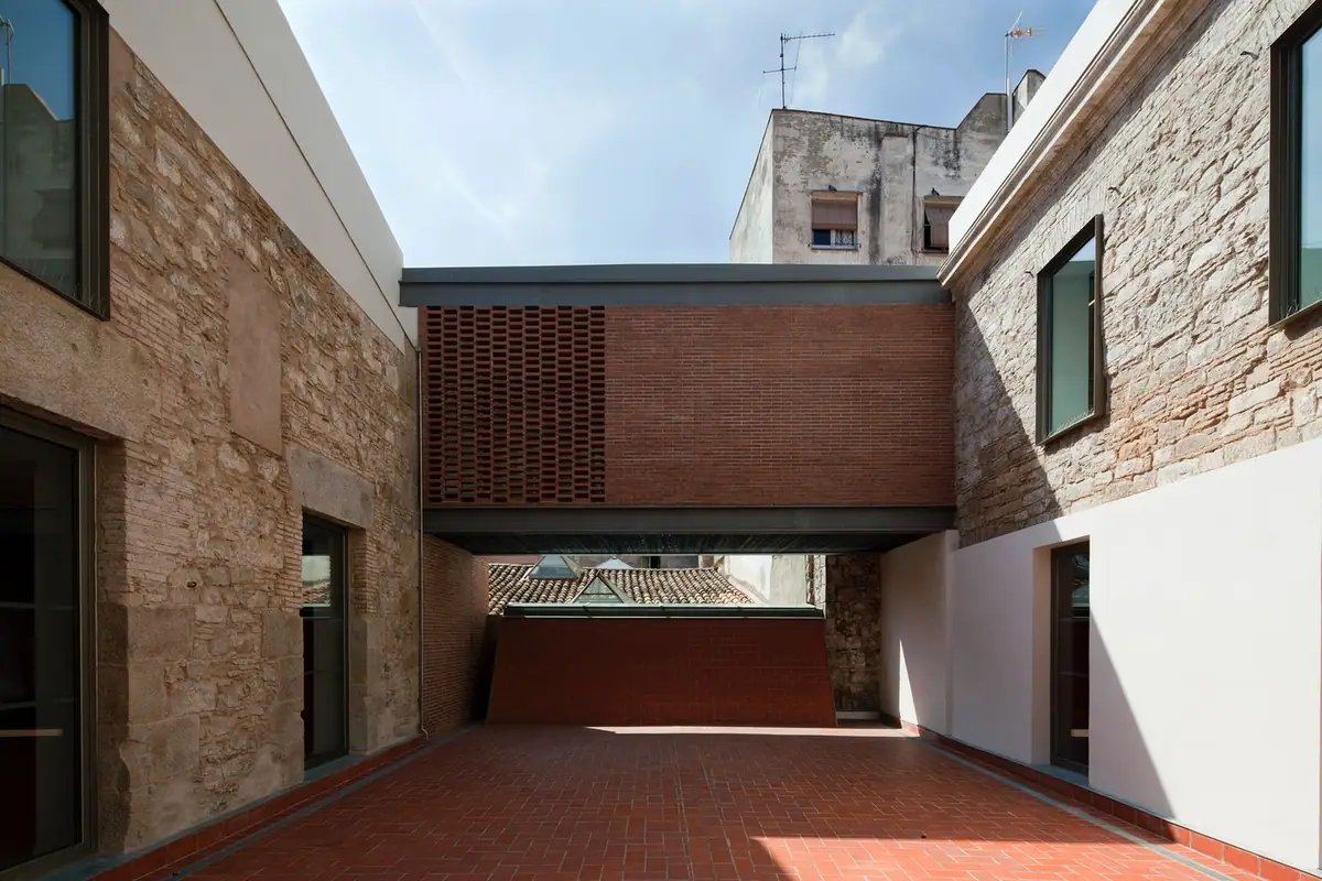 Cuerpo puente de ladrillo que cruza el patio entre dos edificios de piedra