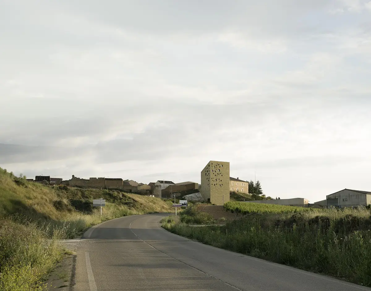 Carretera de acceso a Roa con la torre de piedra de la sede en el borde del pueblo