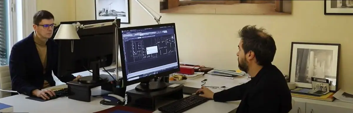 Dos arquitectos trabajan frente a sus ordenadores en un despacho con fotografías de arquitectura en las paredes