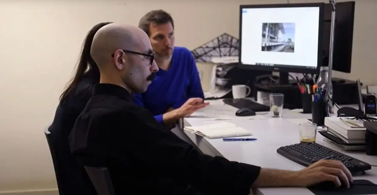 Tres miembros del equipo revisan juntos una imagen de un edificio en la pantalla de un ordenador