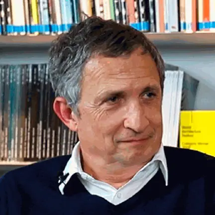 Retrato de Enric Batlle durante la entrevista, frente a una estantería de revistas de arquitectura