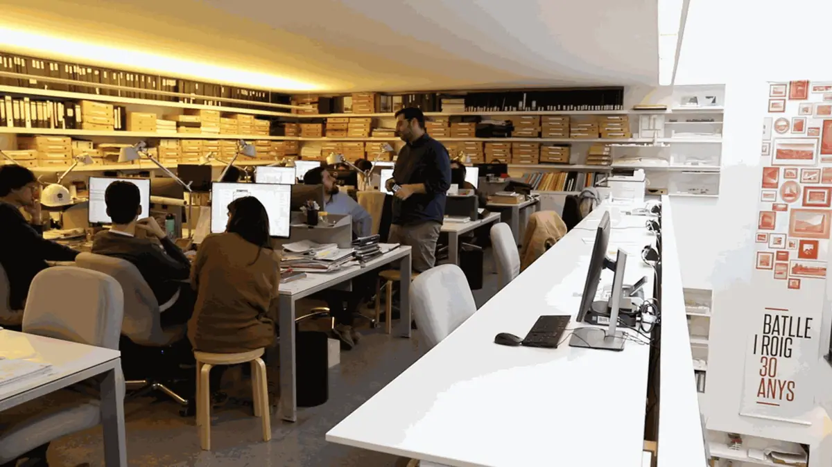 Equipo trabajando en la planta del estudio, con archivos en las estanterías y un cartel por los 30 años de Batlle i Roig