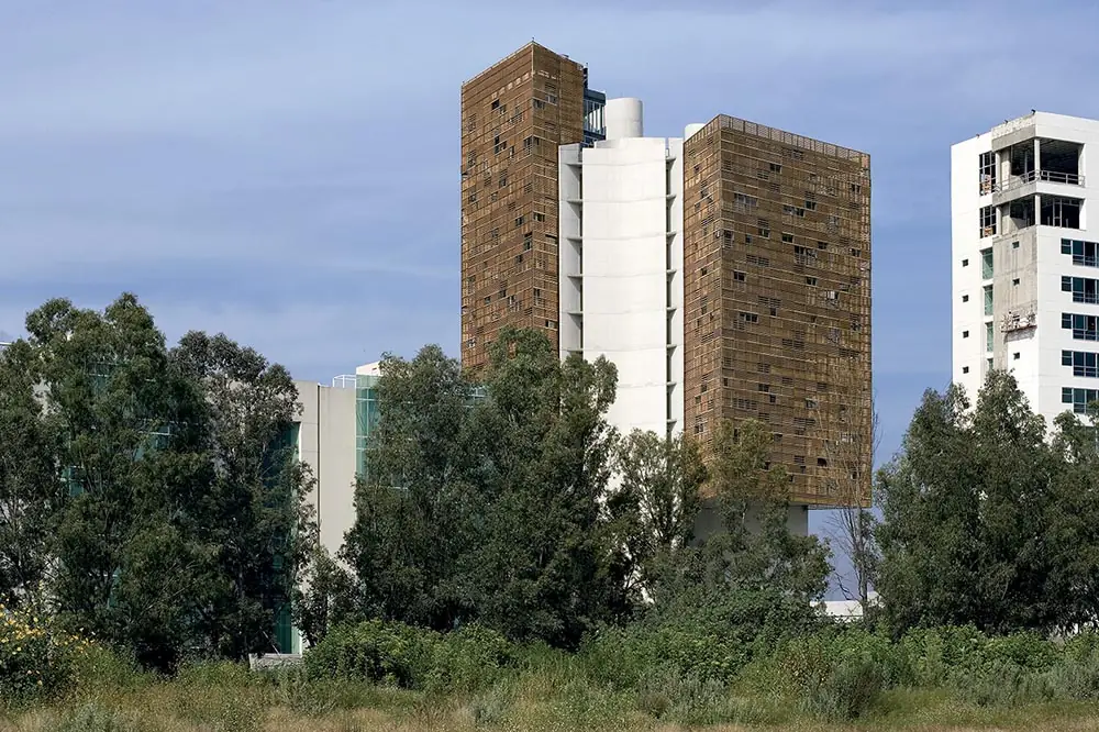 Torre de oficinas Cube con fachada de celosía de madera entre árboles en Guadalajara