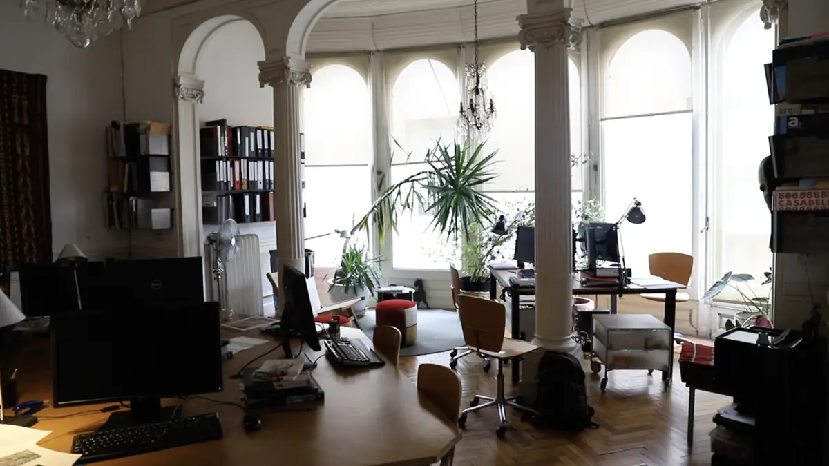 Planta del estudio con columnas clásicas, mesas de trabajo y ventanales en arco