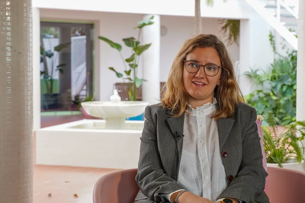 Carlota de Gispert, con gafas y americana gris, durante la entrevista en un patio con plantas y una fuente