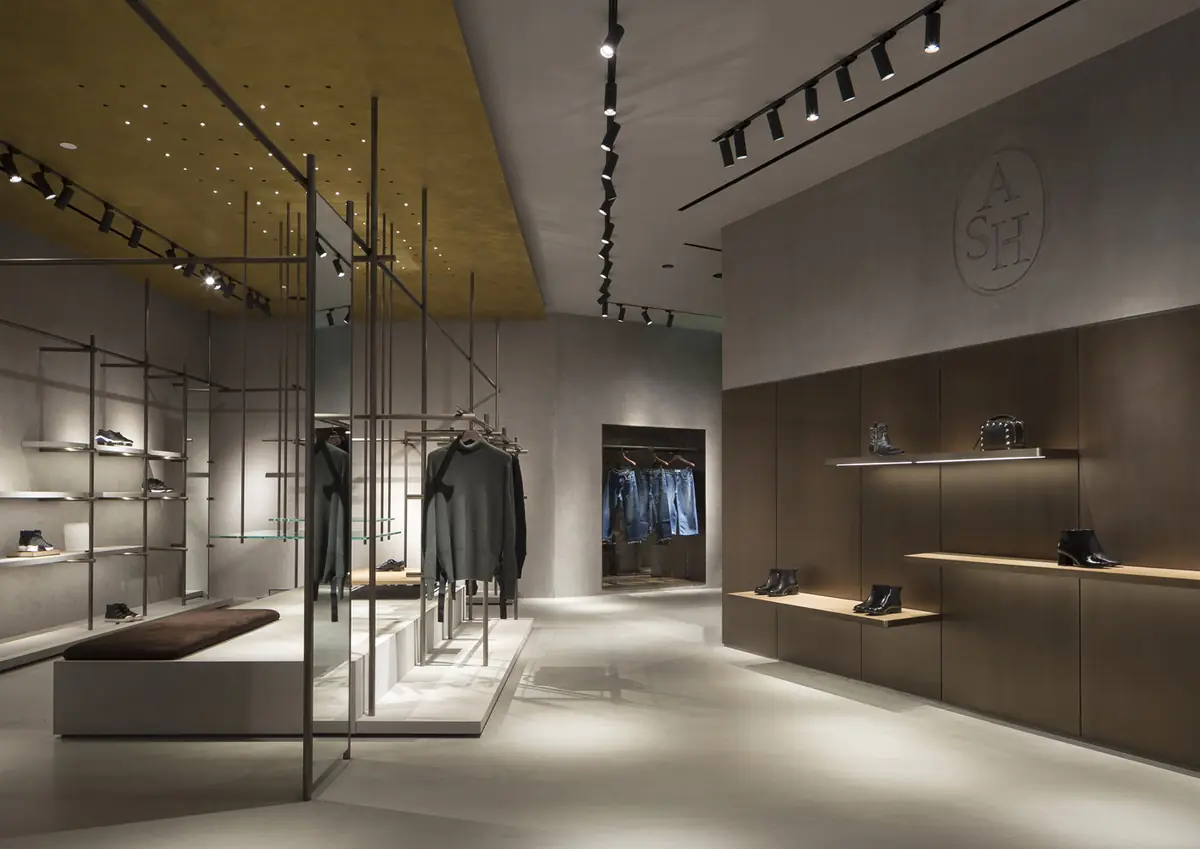 Interior de una tienda de ASH en Shanghái con estructuras tubulares metálicas, techo dorado y estantes de madera