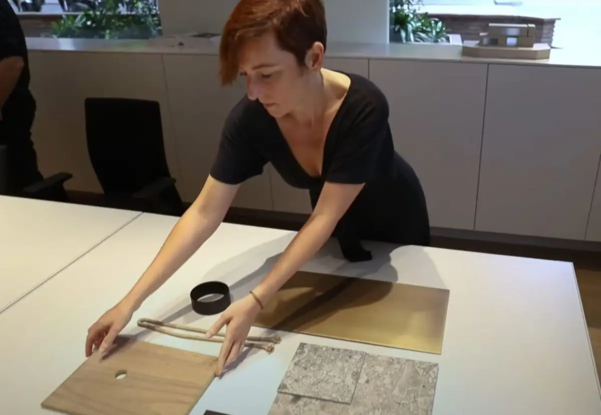 Una interiorista coloca muestras de madera, metal y piedra sobre una mesa del estudio