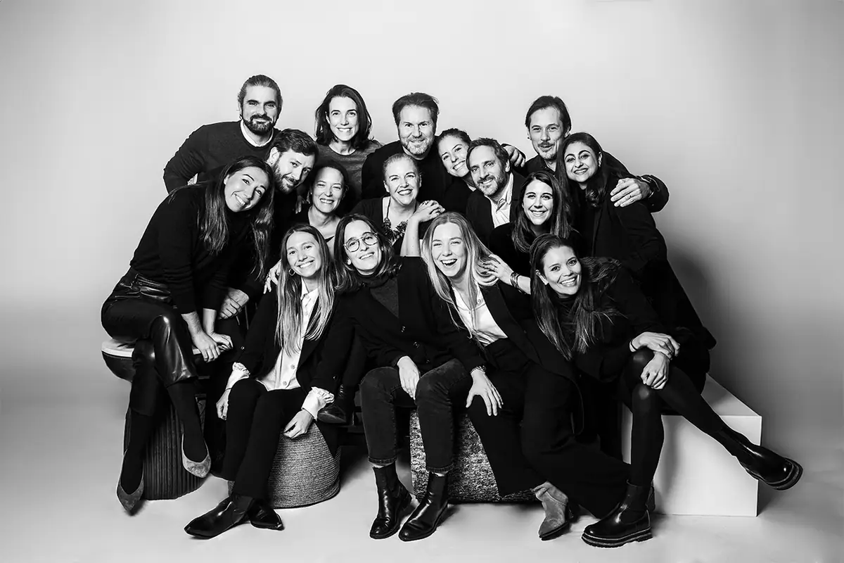 Retrato en blanco y negro del equipo de Gronda, sonriente y agrupado sobre taburetes en un estudio fotográfico