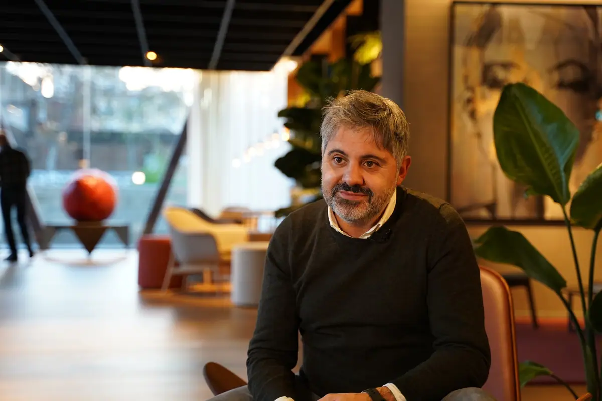 Ernest Boronat, con jersey oscuro, durante la entrevista en una zona de estar con plantas y una gran esfera roja al fondo