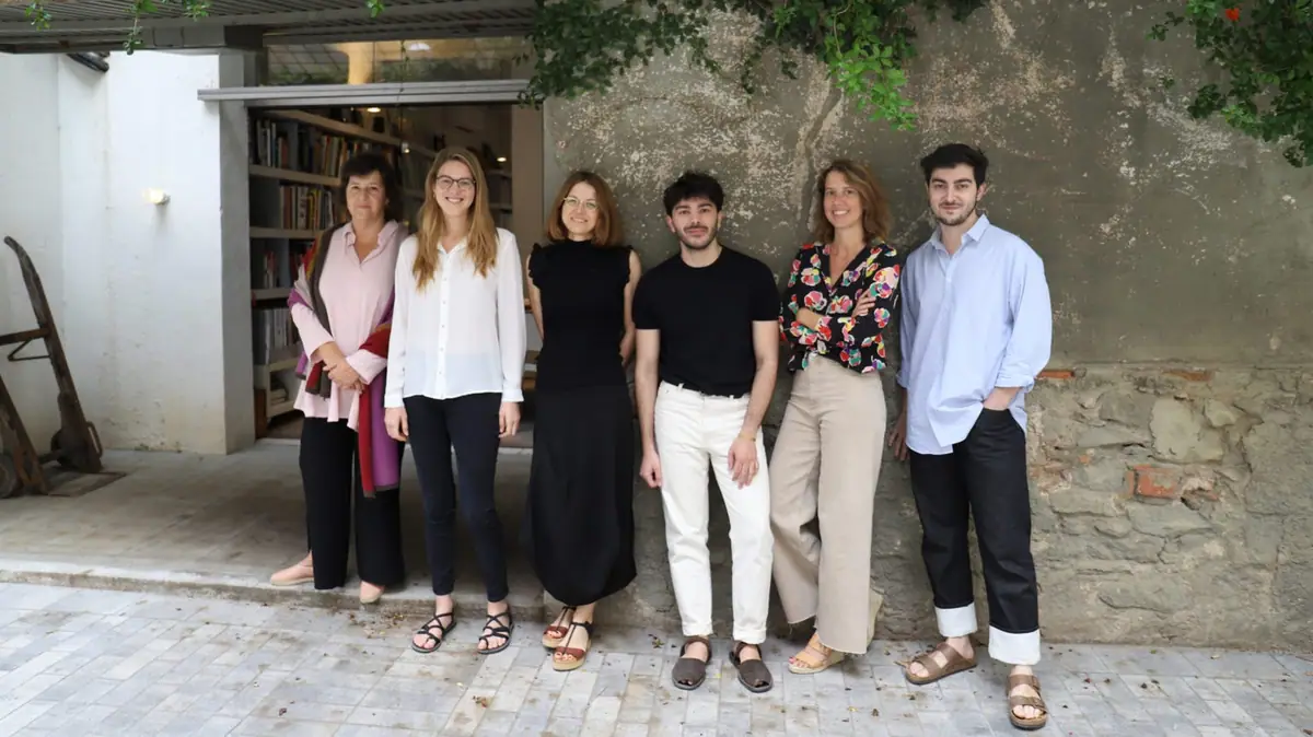 Isabel López Vilalta y cinco miembros de su equipo posan ante un muro de piedra junto a la entrada del estudio