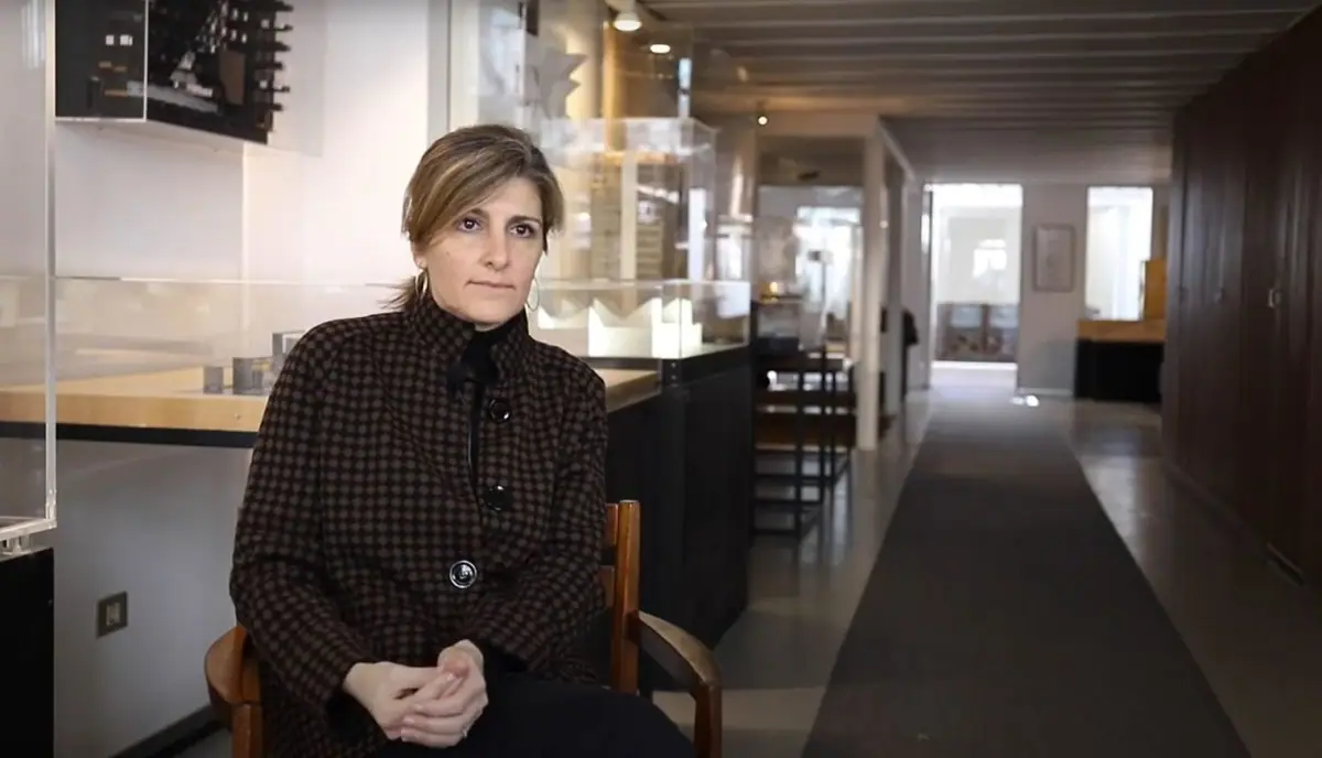 Lucía Ferrater sentada durante la entrevista, con vitrinas de maquetas a su espalda
