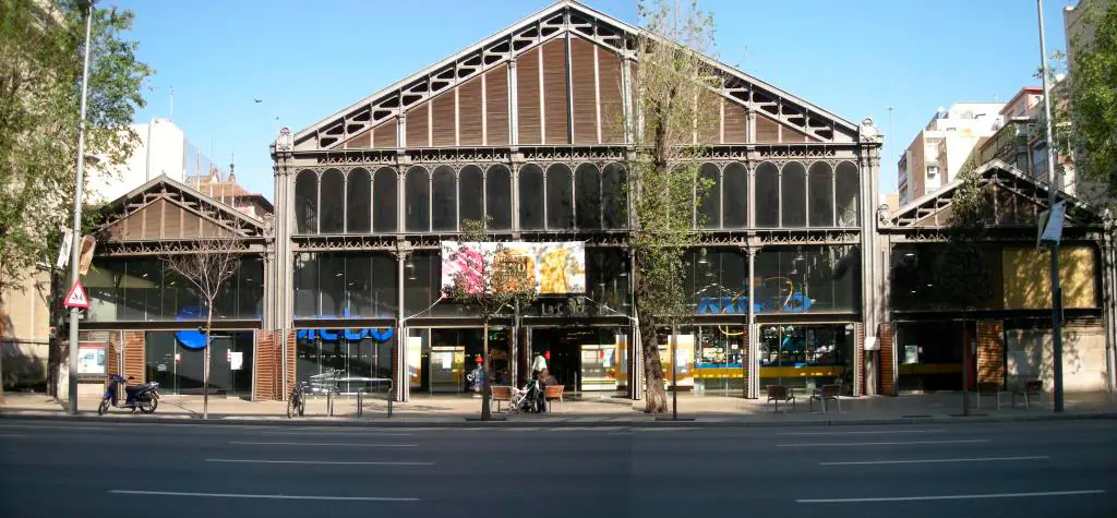 Fachada del Mercat de la Concepció con su nave central de hierro y vidrio y dos naves laterales