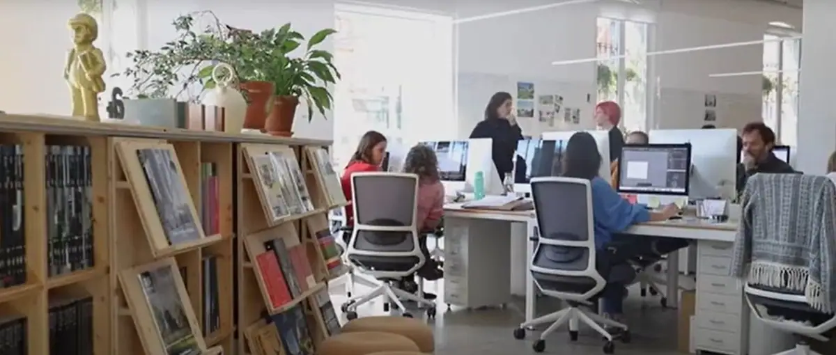 Equipo de PMMT trabajando en una planta libre, junto a una estantería de madera con libros y revistas