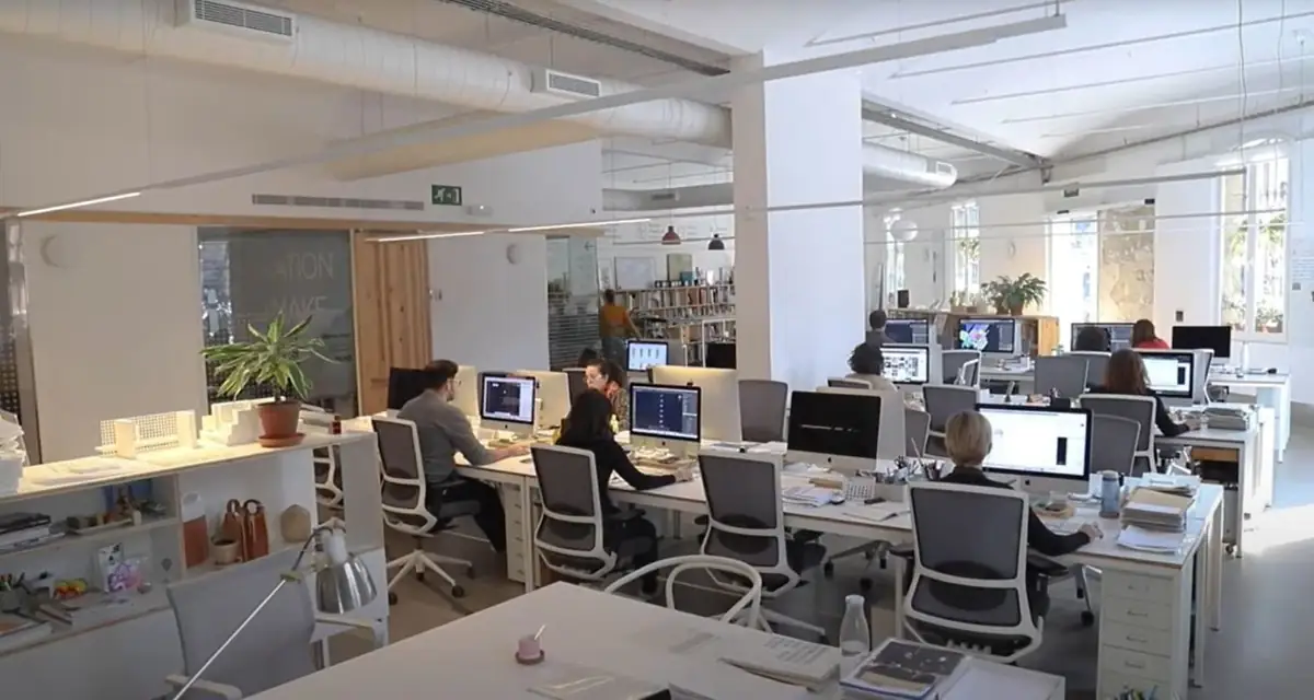 Vista general de una amplia planta de oficinas con puestos de trabajo, instalaciones vistas y salas acristaladas al fondo