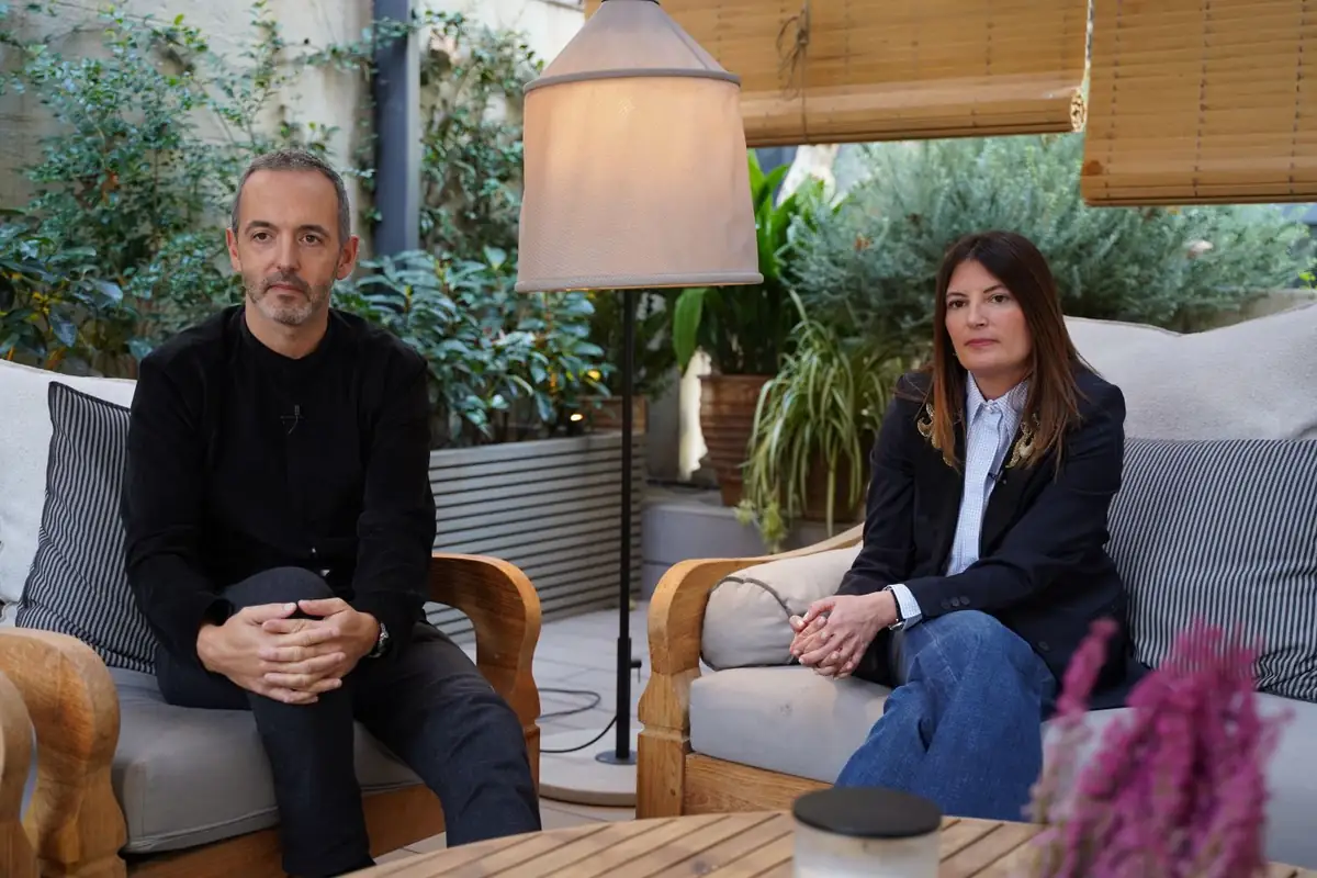 Josep Puigdomènech y Meritxell Ribé en dos butacas de madera junto a una mesa baja y una lámpara de pie